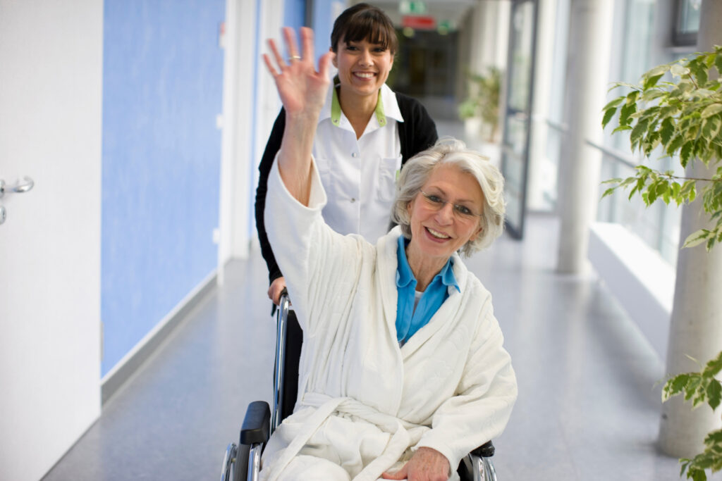 caregiver wheeling elderly woman in wheelchair