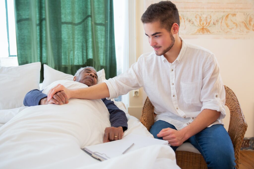 caregiver holding the hand of elderly patient on a bed